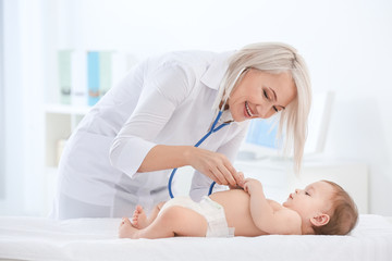 Mature female doctor examining baby boy in clinic