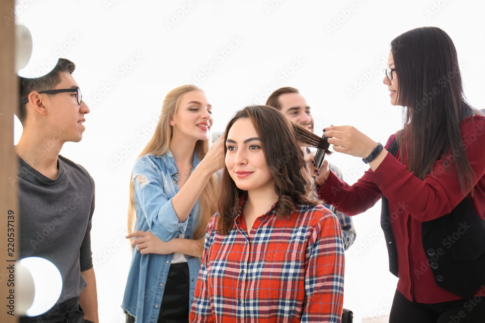 Professional hairdresser and trainees working with client in salon. Apprenticeship concept