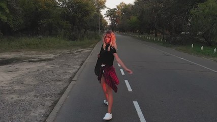 Wall Mural - A young girl in white shorts and a black T-shirt is riding on a skateboard at sunset in the evening. Sunset. Sports and fitness. Slow motion. Aerial Filming