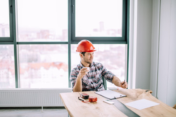 Wall Mural - handsome engineer is holding a cup of tea in the office room. coffee break concept