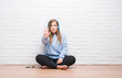 © Krakenimages.com - Young adult woman over white brick wall listening music wearing headphones with open hand doing stop sign with serious and confident expression, defense gesture