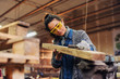 © Dusan Petkovic - Picture of middle age focused female carpenter looking and choosing wood for her work in a workshop.