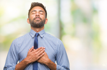 Adult hispanic business man over isolated background smiling with hands on chest with closed eyes and grateful gesture on face. Health concept.