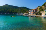Fototapeta  - View of a bay with turquoise waters and traditional colorful houses in Assos village, Kefalonia, Greece