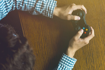 Wall Mural - close up person's hands playng video game isolated on wooden table concept