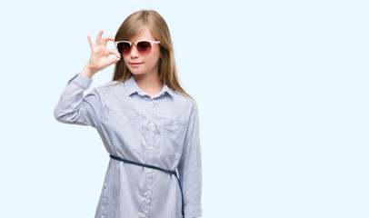 Sticker - Young blonde toddler wearing blue shirt doing ok sign with fingers, excellent symbol