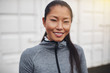 © Flamingo Images - Smiling young Asian woman in sportswear standing outside