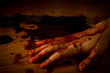 © pimpampix - A hand of a dead person soaked in blood on the floor with a knife in a murder or suicide scene. Also for Halloween.