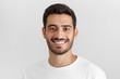 © Damir Khabirov - Headshot of young handsome european caucasian man isolated on gray background, smiling happily and friendly at camera, wearing casual white t-shirt, looking confident and relaxed