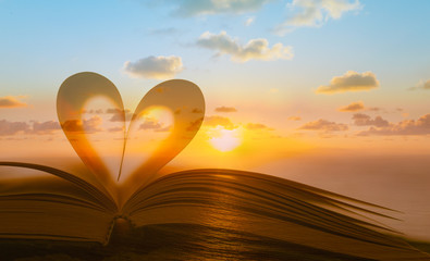 Wall Mural - Book heart against beautiful sunset.Reading, love, romance and religion concept. Double exposure.