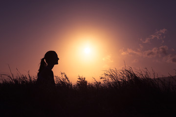 Canvas Print - Young woman sitting out doors relaxing watching the beautiful sunset. People feeling at peace in nature. 