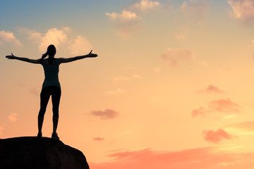 Happiness and freedom.Young woman on a mountain with arms up enjoying the beautiful sunset. 