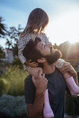 Father carrying his daughter on shoulders at field