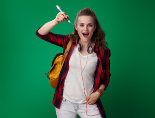 Wall Mural - student woman writing in air with big pen on green background