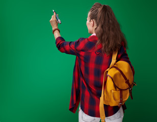 Wall Mural - student woman writing in air with big pen on green background