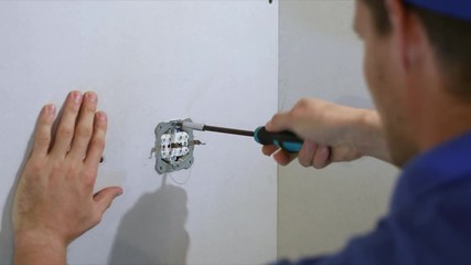 Wall Mural - electrician installing electrical outlet on the wall