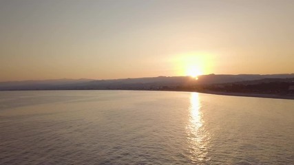 Wall Mural - Tramonto oltre la silhouette delle montagne controluce in riva al mare. Vista aerea.
