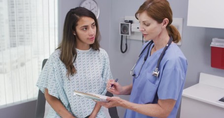 Wall Mural - Portrait of hispanic woman going over health history with senior nurse