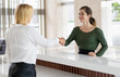 Office receptionist greeting corporate partner with handshake. Woman in formal clothing shaking hands over reception counter. Partnership concept