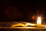 Fototapeta  - a bible on the table in the light of a candle