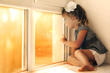 the child is looking in the spring window