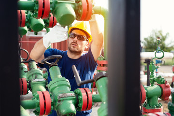 Wall Mural - Oil worker is checking the oil pump on the sunset background