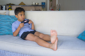 Canvas Print -  Latin young child 8 years old excited and happy playing video game online holding remote controller enjoying having fun lying on couch in internet gaming