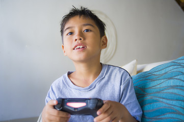 Canvas Print -  Latin young child 8 years old excited and happy playing video game online holding remote controller enjoying having fun sitting on couch in internet gaming