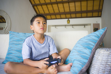 Wall Mural -  Latin young kid 8 years old excited and happy playing video game online holding remote controller enjoying having fun on couch in child gaming addiction