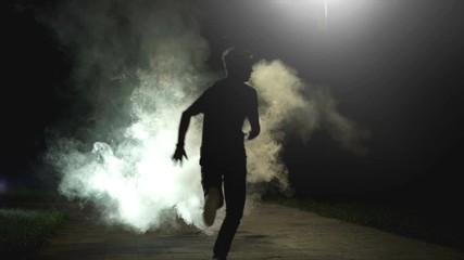 the fellow running in the cloud of smoke on the dark background, slow motion