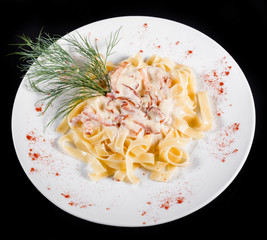 Fettuccine pasta with meat, cream sauce and herbs, in bowl isolated on black background. Italian cuisine. Top view