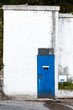Isolated white wall of narrow building with blue door, vintage