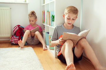 Happy children reading books on the floor at the school  library