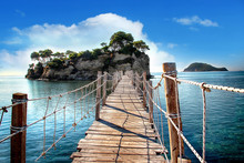 The Wooden Bridge Overlooking The Sea Leads To An Island With Palm Trees. It's A Rope Bridge. It Is Located In Zakynthos, Greece.