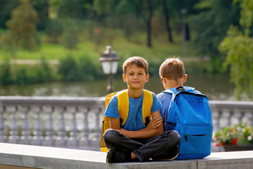 Primary education, back to school, friendship, childhood, communication and people concep - kids with backpack sitting outdoors