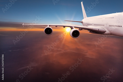 Fotografía  Big commercial airplane flying above dramatic clouds.