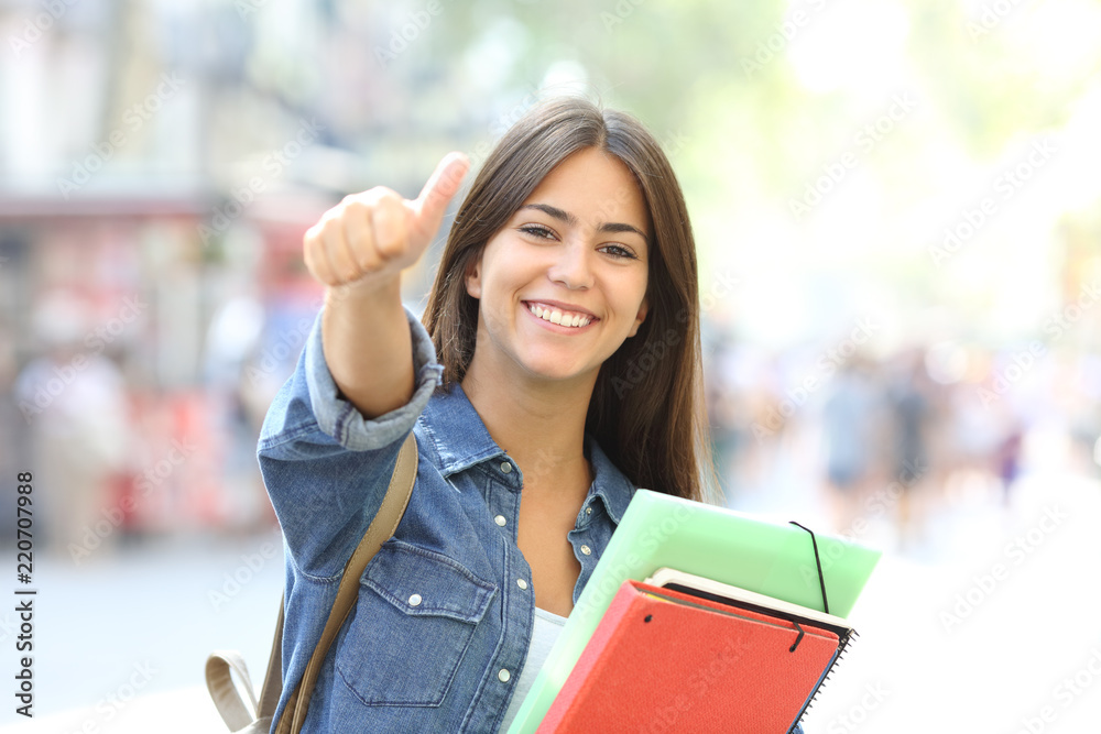 Happy student posing with thumbs up in the street - obrazy, fototapety, plakaty 