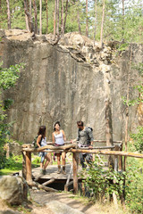 Wall Mural - Young friends on wooden platform near rocky mountain. Camping season