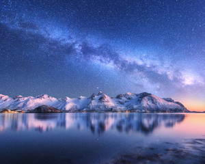Wall Mural - Bright Milky Way over snow covered mountains and sea at night in winter in Norway. Landscape with snowy rocks, starry sky, reflection in water, fjord. Lofoten Islands. Space. Beautiful milky way