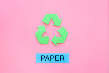 Types of matherial for reycle and reuse. Printed word paper near eco symbol recycle arrows on pink background top view copy space