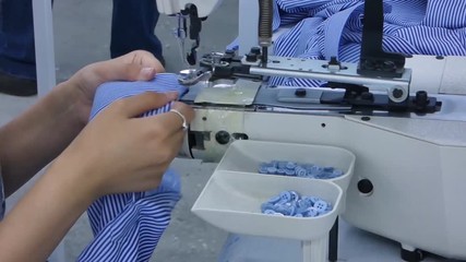 Wall Mural - the woman in the workshop sews buttons to the shirt