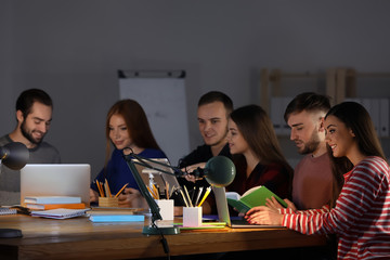 Canvas Print - Students doing homework together indoors late at night