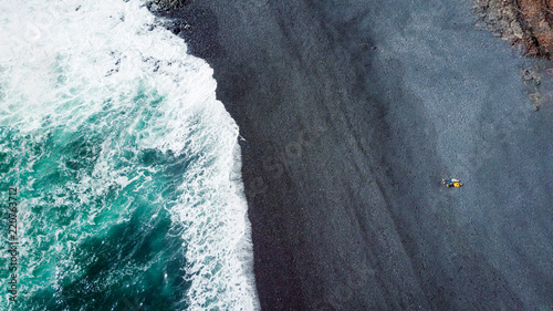 aerial-view-of-couple-lying-on-grey-sand-near-sea-djpalnssandur-beach-iceland