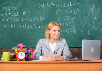 Wall Mural - Teacher cheerful pleasant woman educator sit table classroom work with laptop. Online job boards or careers pages. Teacher happy work in school chalkboard background. Teacher job description