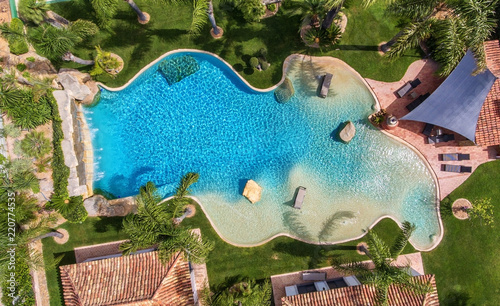 Original decorative pool in the garden with palm trees, aerial view.