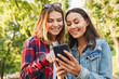 © Drobot Dean - Women friends students walking in the park using mobile phone.