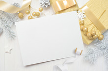 Abstract Christmas Background, White Sheet Of Paper Lying Among Small Decorations On White Wooden Desk. Flat Lay Mockup For Your Art, Picture Or Hand Lettering Composition Copy Space, Top View