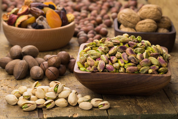 Wall Mural - pistachios nuts peeled in wooden bowl on table, grunge style.