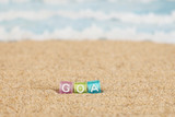 Fototapeta  - Word GOA from multicolored cubes in the sand on the background of beach and sea