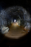 Fototapeta Perspektywa 3d - Light from a flashlight shining through a narrow cave in the tow